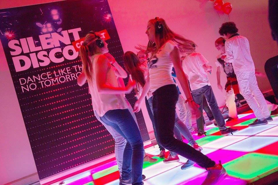 Mensen dansen met draadloze koptelefoons tijdens een silent disco evenement.
