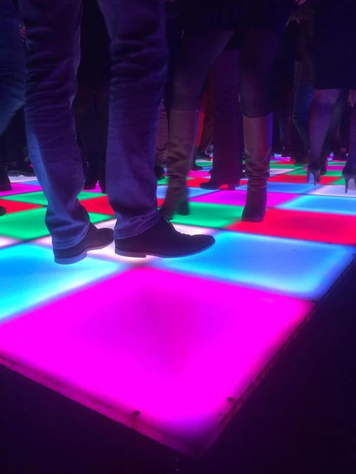 Personen dansen op een kleurrijke, verlichte dansvloer.