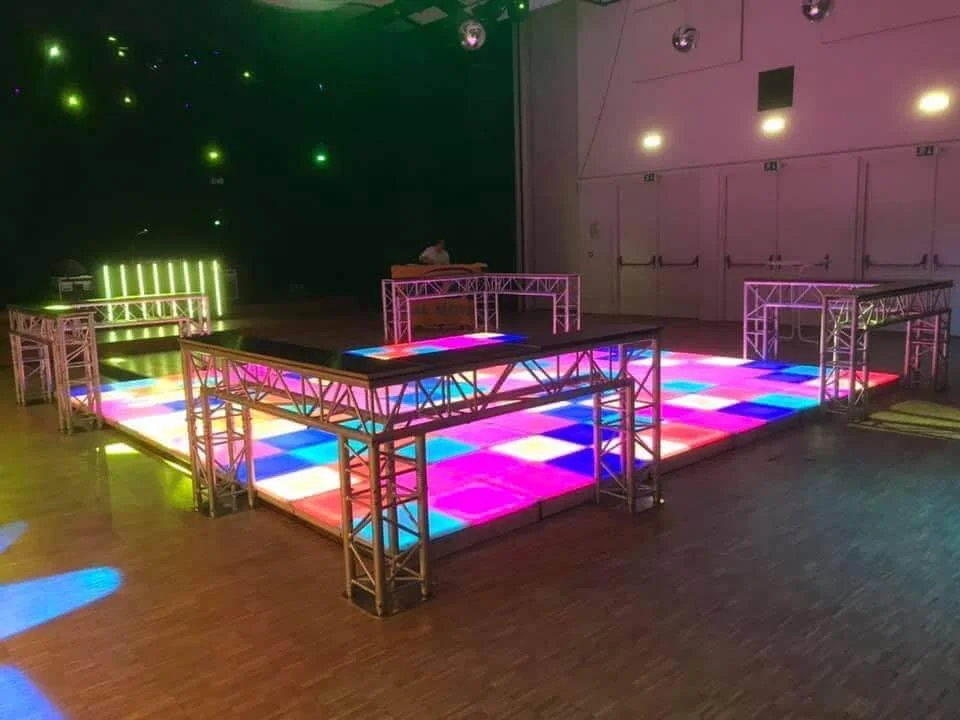 Verlichte dansvloer met kleurrijke lichten in een zaal met metalen constructies.