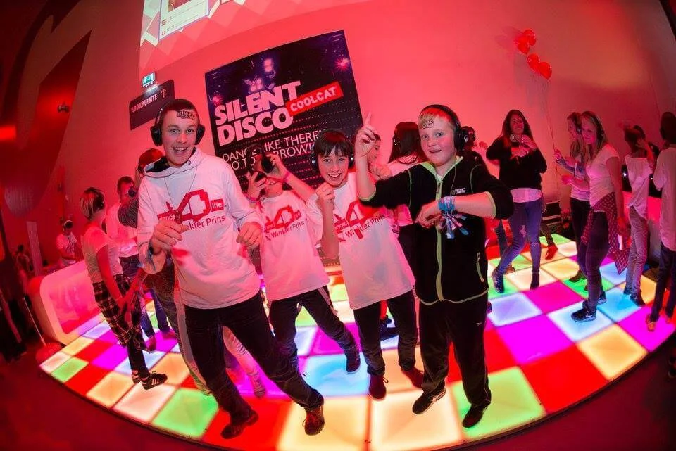 Kinderen dansen op een verlichte dansvloer tijdens een silent disco.